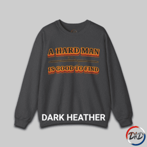 A Dark Heather unisex fit crewneck sweatshirt featuring bold retro orange‑and‑brown typography that reads “A Hard Man Is Good to Find,” with a vintage curved accent line and star between the text lines.