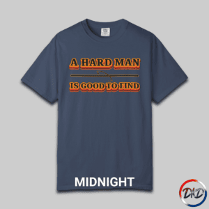 A Midnight Comfort Colors® 1717 T‑shirt featuring bold retro orange-and-black typography that reads “A Hard Man Is Good to Find,” with a small vintage accent graphic between the lines.