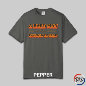A Pepper Comfort Colors® 1717 T‑shirt featuring bold retro orange-and-black typography that reads “A Hard Man Is Good to Find,” with a small vintage accent graphic between the lines.